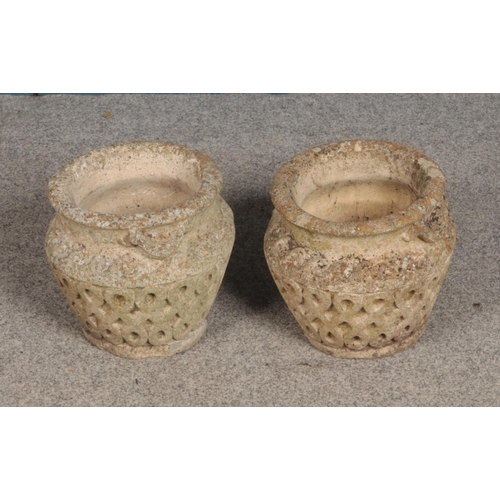 343 - A pair of stone urns with carved lattice design. Approx. 28cm tall.