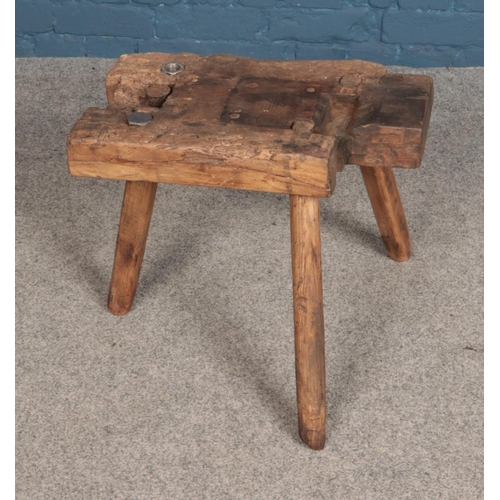 556 - A three legged wooden stool with nut and bolt detail.