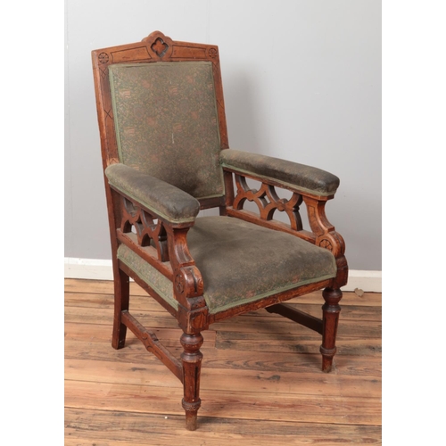 506 - A carved pitch pine arm chair with armorial upholstery.