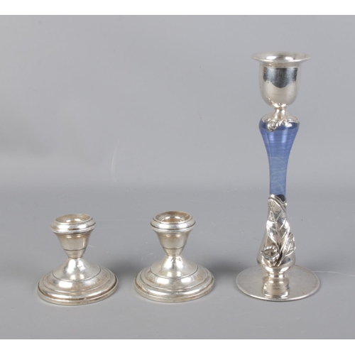 135 - A pair of weighted sterling silver candlesticks with larger white metal example featuring leaf desig... 