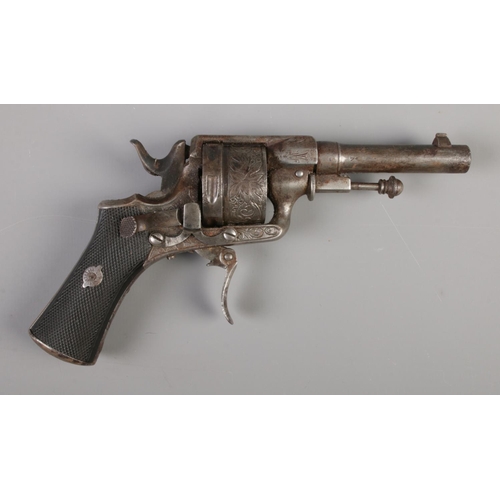 58 - A late 19th/early 20th century pin fire revolver with engraved six shot cylinder and chequered grip.