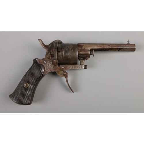 59 - A late 19th/early 20th century pin fire revolver with engraved six shot cylinder and chequered grip.