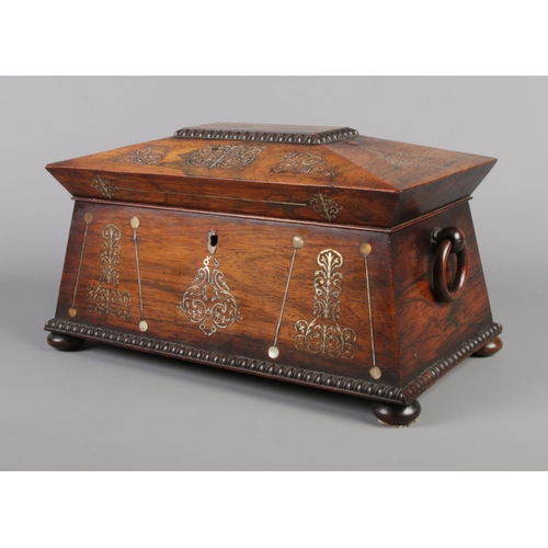 73 - A Victorian rosewood tea caddy of sarcophagus form, having mother of pearl inlay and wooden loop han... 