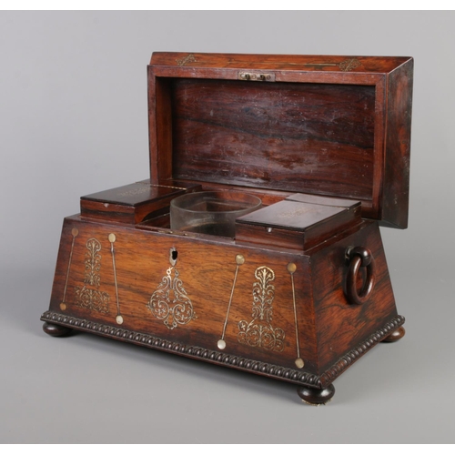 73 - A Victorian rosewood tea caddy of sarcophagus form, having mother of pearl inlay and wooden loop han... 