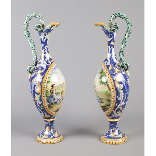 19 - A pair of Majolica ewers decorated with classical scenes and having intertwined serpent handles. 42c... 