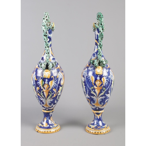 19 - A pair of Majolica ewers decorated with classical scenes and having intertwined serpent handles. 42c... 