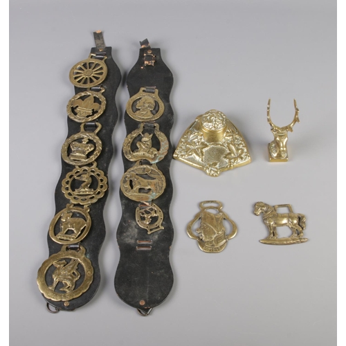 246 - A quantity of brass including inkwell, stag figure and several buckles displayed on leather strap.