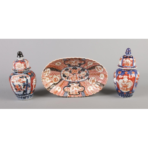 147 - A Japanese Imari fluted oval dish along with a pair of similar lidded vases.