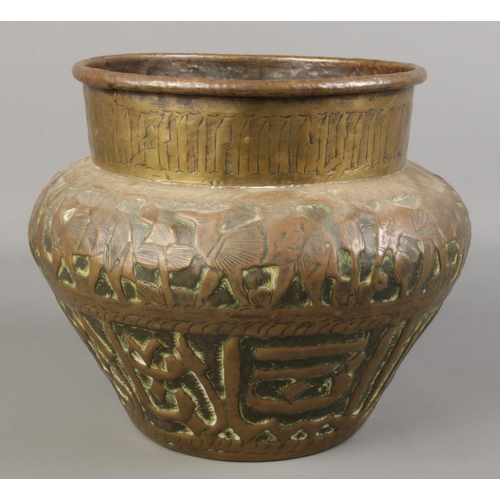 120 - An Eastern brass planter decorated with animals. Height 20cm.