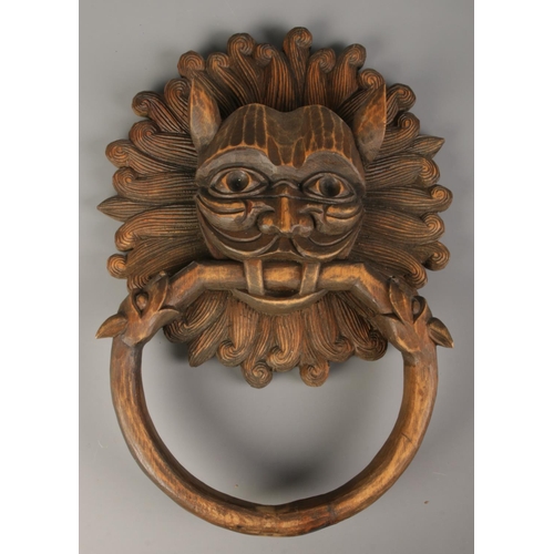 125 - A carved wooden mask formed as a sanctuary door knocker. Signed to the back J. Sarabia. 41cm x 31cm.