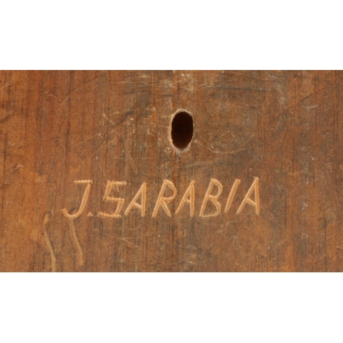 125 - A carved wooden mask formed as a sanctuary door knocker. Signed to the back J. Sarabia. 41cm x 31cm.