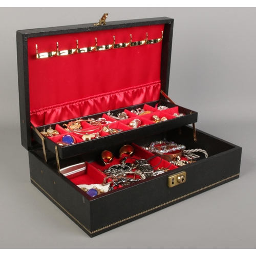 161 - A large black cantilever jewellery box containing a collection of costume jewellery, including brooc... 