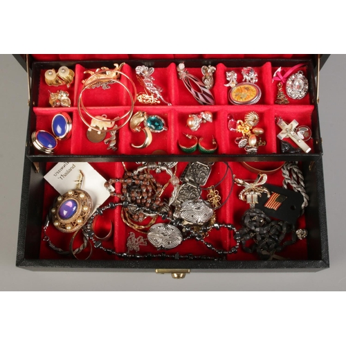 161 - A large black cantilever jewellery box containing a collection of costume jewellery, including brooc... 