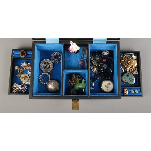 165 - A musical jewellery box containing an assortement of costume jewellery; including white metal charms... 