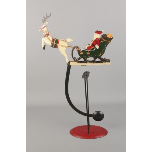 26 - A painted metal rocking Father Christmas with sleigh and reindeer ornament. Approx. 55cm tall when s... 