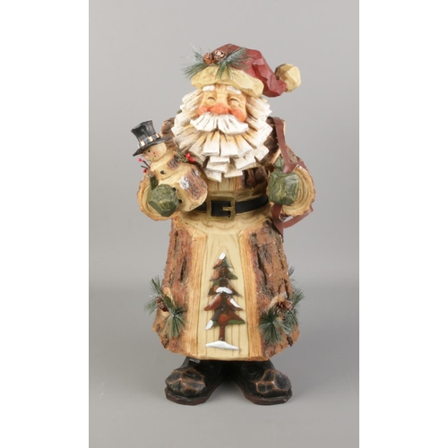 28 - A carved and painted wooden figure of Father Christmas delivering presents. Approx. 47cm tall.