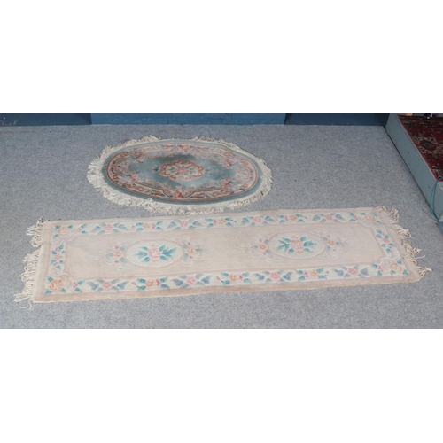 312 - Two floral rugs with decorative fringe. Includes oval and rectangular example.