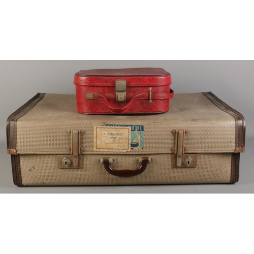 315 - A large vintage suitcase, together with a red faux leather vanity case (empty).