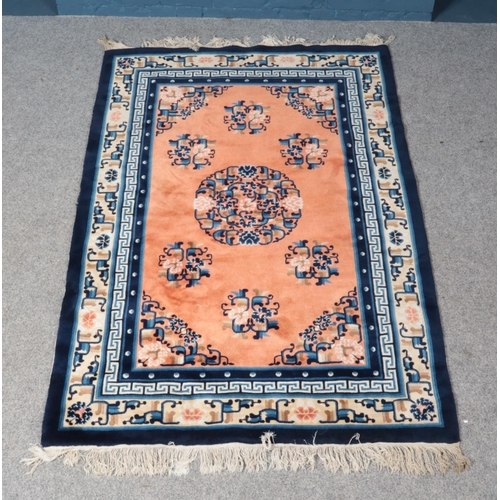 322 - A Chinese style blue ground wool rug, with geometric design and frayed edges with central medallion ... 