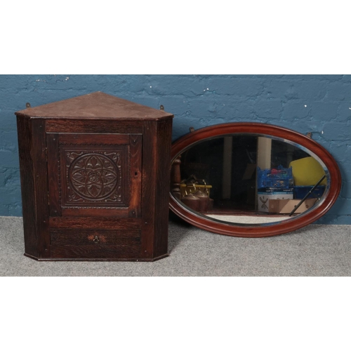 326 - An arts and crafts style corner cupboard with lower drawer and key, together with a large oval mirro... 