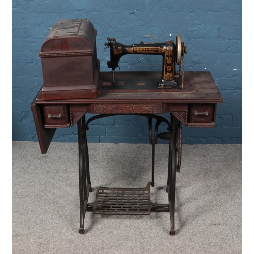 331 - A Wheeler & Wilson treadle sewing machine with various accessories including buttonholer, bobbins an... 