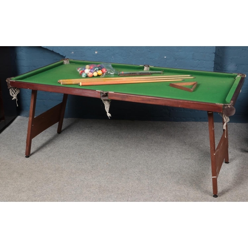 340 - A slate pool table with accessories to include balls, cues etc.