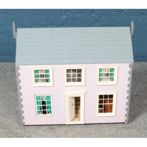 342 - A pink child's dollhouse including accessories such as furniture and dolls. Some damage to windows. ... 