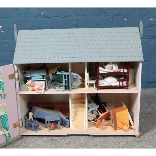 342 - A pink child's dollhouse including accessories such as furniture and dolls. Some damage to windows. ... 