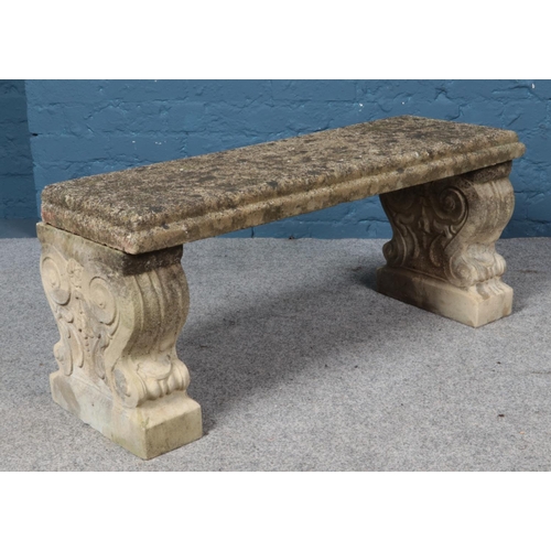 365 - A concrete garden bench raised on two decorative pedestals. Length of top 100cm.