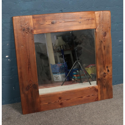 389 - A large wooden framed rustic style wall mirror. Dimensions including frame approx. 96cm x 92cm.