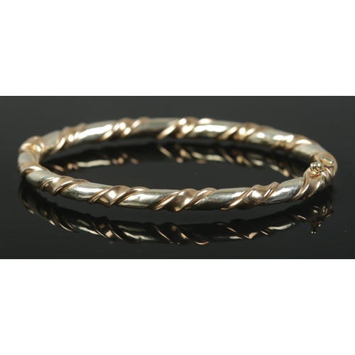 438 - A 9ct Gold bangle with twisted decoration and hinged clasp. Total weight: 9.95g