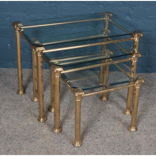 545 - A set of three glass topped nesting tables with brass frames. Largest table dimensions 64cm x 40cm x... 