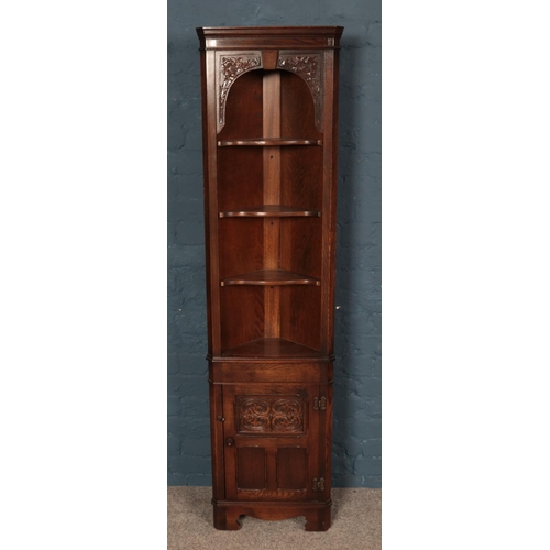 557 - A Jaycee carved oak slender corner cabinet.