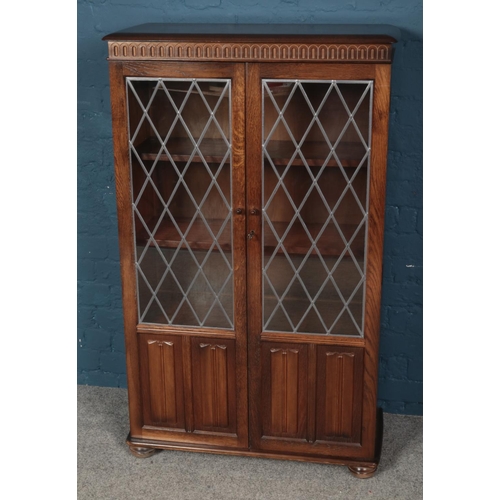 560 - A Priory style oak bookcase with lead glazed glass panel doors. (132cm x 81cm)