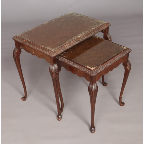 487 - A pair of walnut nesting tables featuring glass tops set on cabriole legs. Largest table approx. 69c... 