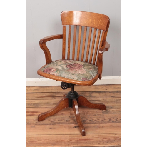 495 - A swivel wooden office chair with upholstered fabric seat.