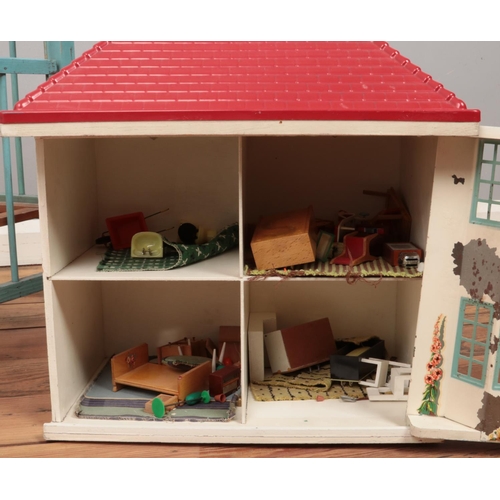 263 - A wood and tin plate dolls house with contents of some furniture, along with a small cot.