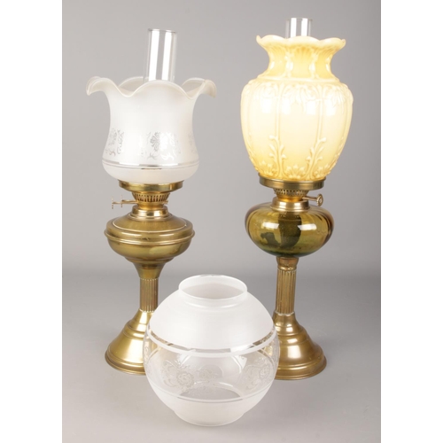 72 - Two brass oil lamps with shades and funnels, along with an additional globular shade.