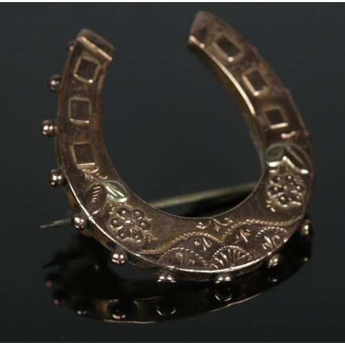 332 - A 9ct gold brooch formed as a horseshoe with floral decoration. 3.56g