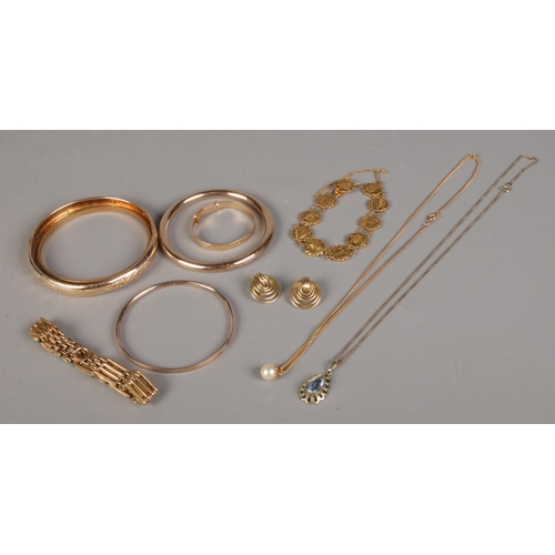 391 - A collection of rolled gold jewellery. To include slave bangles, pendant on chain, gate bracelet and... 