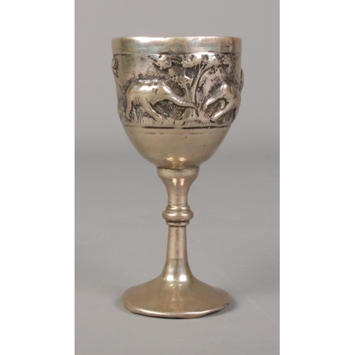 433 - A white metal, possibly silver, goblet featuring rainforest scene with village huts and elephants. W... 