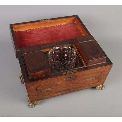 109 - A Regency tea caddy of sarcophagus form. With cut glass bowl, brass lion paw feet, inlaid brass deta... 
