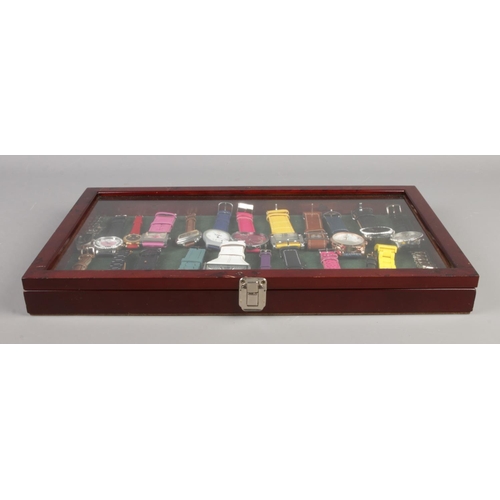 110 - A small hinged table top bijouterie cabinet containing an assortment of quartz wristwatches. To incl... 