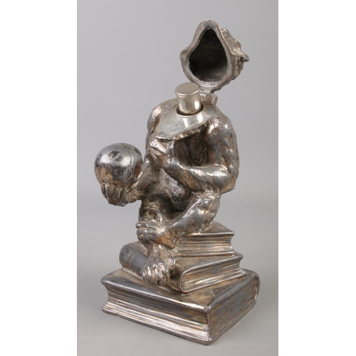 6 - A white metal table lighter formed as a monkey holding a skull. 16cm.