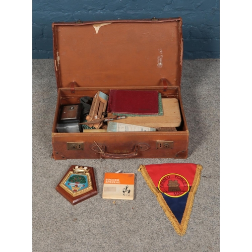 310 - A leather suitcase containing an assortment of collectables including Armed Forces of Malta banner, ... 