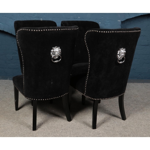 543 - Four black button back dining chairs with studded edges and lion pull handle detail.