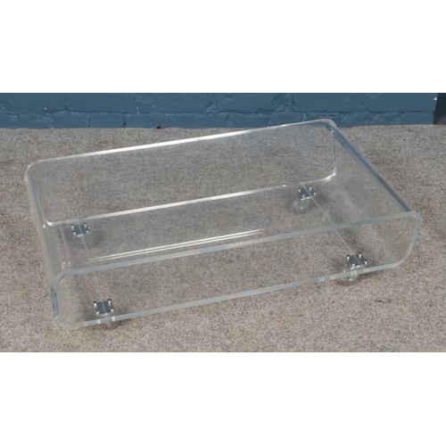 555 - A clear acrylic/Perspex two-tier coffee table. Approx. dimensions 83cm x 50cm x 26cm.