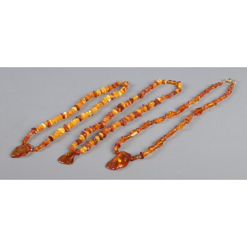 435 - Three amber/copal and composite necklaces, with large pendant pieces. 66.36g.