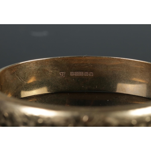 407 - A 9ct gold bangle featuring engraved floral decoration. 18.4g