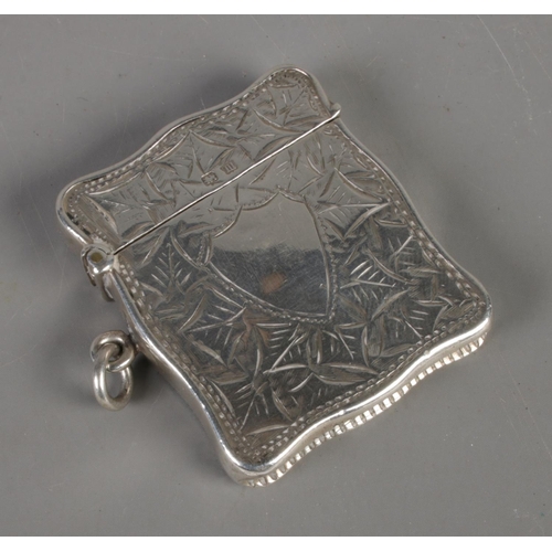 448 - A George V silver vesta case, with ivy leaf detailing and central shield crest. Clear hallmarks for ... 